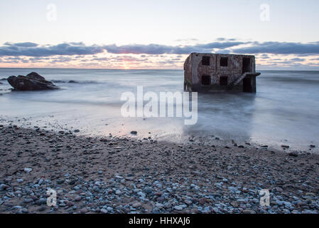 Le concassage des pierres et des vagues ruines du vieux fort au coucher du soleil sur la plage Banque D'Images