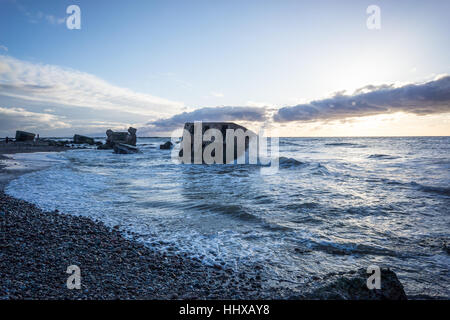 Le concassage des pierres et des vagues ruines du vieux fort au coucher du soleil sur la plage Banque D'Images