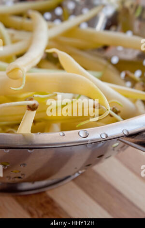 Tas de haricots jaunes fraîches dans une passoire métallique sur une table en bois Banque D'Images