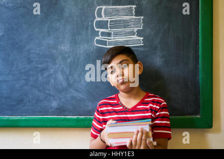 Concept sur tableau noir à l'école. Les jeunes, d'étudiants et d'élèves en classe. Triste et ennuyé hispanic boy en classe. Portrait d'enfant de sexe masculin à la recherche à Banque D'Images