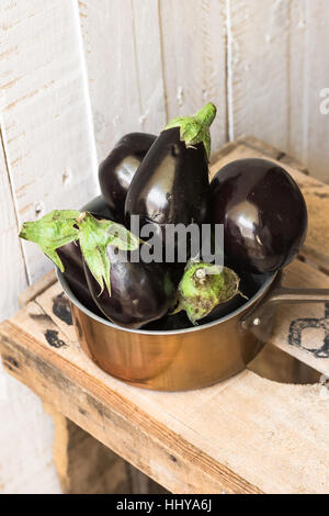 Bébé violet aubergines dans un balancier de cuivre sur bois vintage fort sur fond blanc,top,vue,style rural été automne, automne Banque D'Images