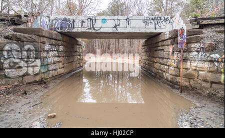 Vieux pont de chemin de fer couverts de graffitis avec chemin de terre sous Banque D'Images