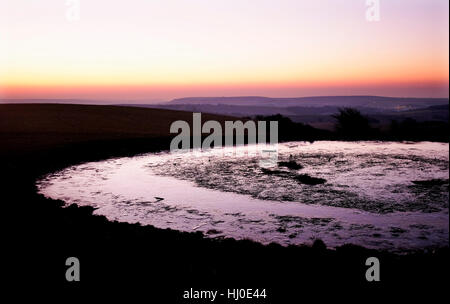 Brighton, Royaume-Uni. 21 janvier 2017. Le soleil se lève par un étang de rosée gelé au-dessus de la South Downs Way à Ditchling Beacon juste au nord de Brighton ce matin avec des températures prévues bien en dessous du point de congélation dans le sud de la Grande-Bretagne crédit : Simon Dack/Alamy Live News Banque D'Images