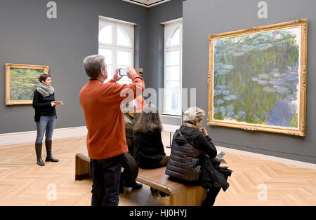 Potsdam, Allemagne. 21 Jan, 2017. Les visiteurs regarder la peinture "Roses" (r) par Claude Monet au Musée Barberini à Potsdam, Allemagne, 21 janvier 2017. Plus de 1 500 personnes ont visité le nouveau musée Barberini de Hasso Plattner mécène dans le centre historique de Potsdam le samedi. 90 œuvres, dont 41 de Claude Moneet ainsi que Pierre-Auguste Renoir et Alfred Sisley peut être vu à l'exposition 'Klassiker der Moderne'. Photo : Bernd Settnik/dpa-Zentralbild/dpa/Alamy Live News Banque D'Images