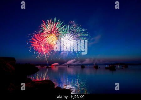 D'artifice de couleurs explosent dans un port du Maine au crépuscule rempli de bateaux. Banque D'Images