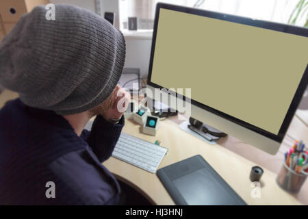 L'homme assis à 24 créatifs travaillant sur les dessins sur un ordinateur en utilisant une tablette graphique. Banque D'Images