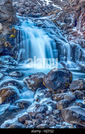 Une cascade en Islande cascades en bas du côté d'une montagne sauvage dans une piscine naturelle. Banque D'Images