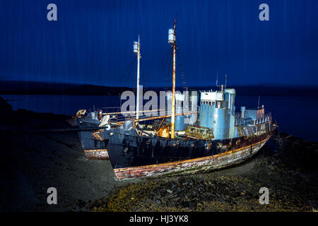 Deux baleinières abandonnées reste sur une plage éloignée après l'Islande à la casse leur programme de chasse à la baleine. Les navires sont peintes dans la nuit avec un feu de forte pluie pour Banque D'Images