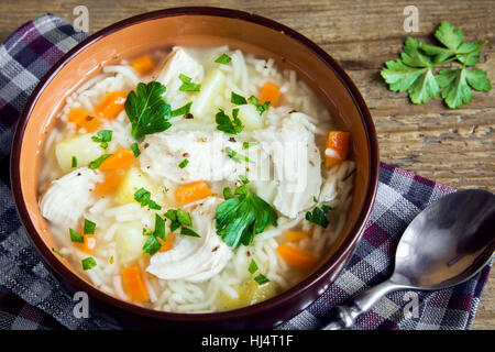Soupe de poulet aux vermicelles et légumes dans un bol au fond rustique en bois - des repas sains Banque D'Images
