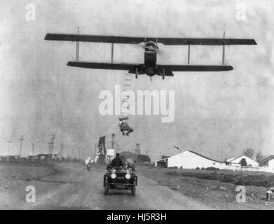 'Freddie sans peur', un cascadeur d'Hollywood, accroché à une échelle de corde suspendue à partir d'un avion piloté par H Maltrup, sur le point de tomber en dessous de l'automobile : automobile illustré. 1921 Banque D'Images