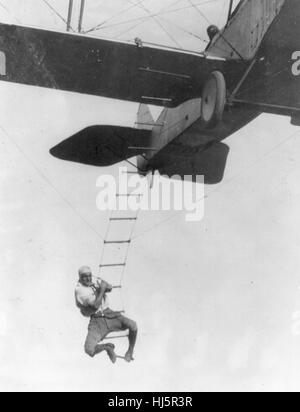 'Freddie sans peur', un cascadeur d'Hollywood, accroché à une échelle de corde suspendue à partir d'un avion piloté par H Maltrup, sur le point de tomber dans l'automobile ci-dessous : l'automobile non illustré, vers 1920 Banque D'Images