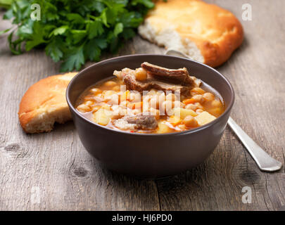 Soupe d'agneau dans un bol de pois chiches, le persil, le pain plat et sur l'ancien fond de bois Banque D'Images