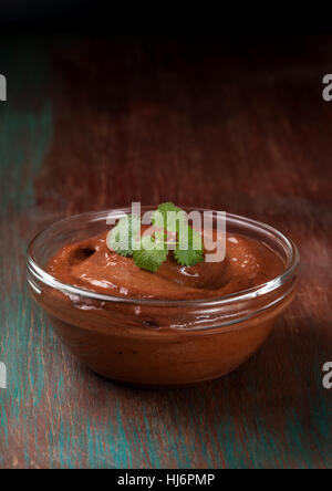 Mousse au chocolat et menthe dans un bol en verre sur un fond de bois