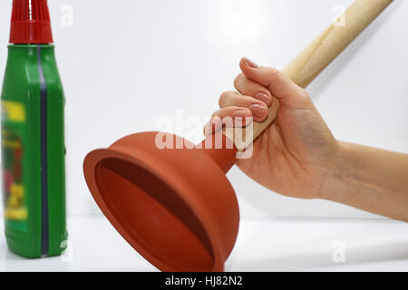 Femme avec piston à essayer d'enlever les puits bouchés. Banque D'Images