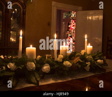 Bougies de Noël dans un arrangement floral rose blanc avec un arbre dans l'arrière-plan Banque D'Images