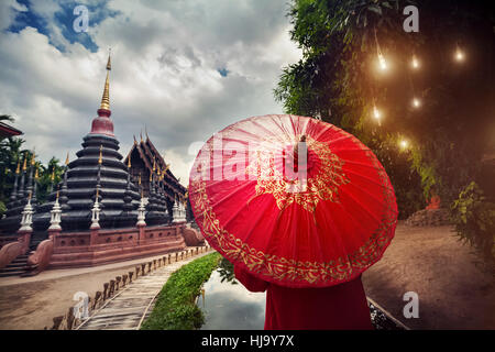 Tourisme Femme avec parapluie traditionnel Thaï rouge dans Black temple Wat Phan Tao dans Chiang Mai, Thaïlande Banque D'Images