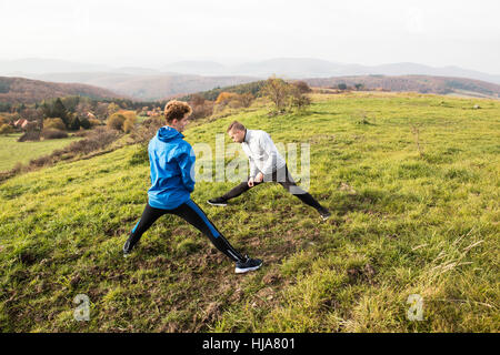 Deux jeunes coureurs hipster à sunny automne nature l'étirement des jambes Banque D'Images