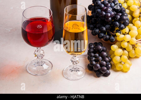 - Deux verres de vin blanc et un vin rouge et une bouteille brune avec du vin blanc sur la lumière en arrière-plan. Banque D'Images