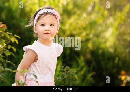 Superbe petite fille à l'extérieur dans le jardin vert Banque D'Images