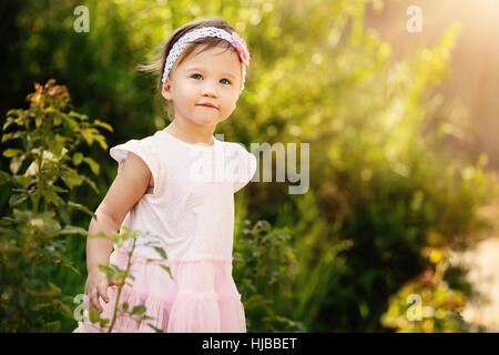 Superbe petite fille à l'extérieur dans le jardin vert Banque D'Images