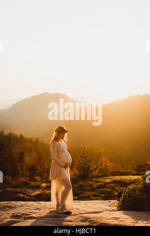 Femme enceinte dans les montagnes de toucher l'estomac, Sequoia National Park, Californie, USA Banque D'Images