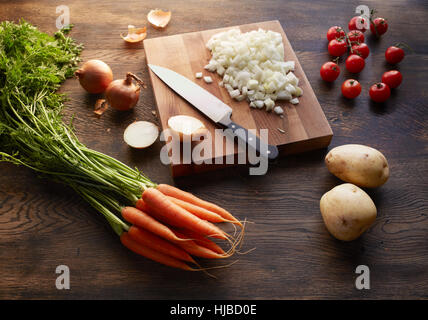 Carottes fraîches, pommes de terre et les tomates cerise avec des oignons hachés sur une planche à découper Banque D'Images