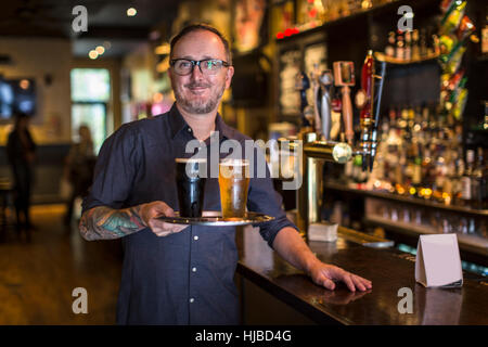 Portrait of mature bartender carrying tray de bière en public house Banque D'Images