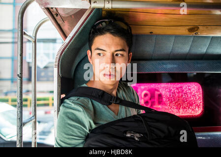 Jeune homme assis à l'arrière de tuk tuk, Chiang Mai, Thaïlande Banque D'Images