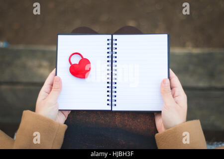 Les mains tenant un ordinateur portable avec cadenas rouge fermé en forme de coeur Banque D'Images