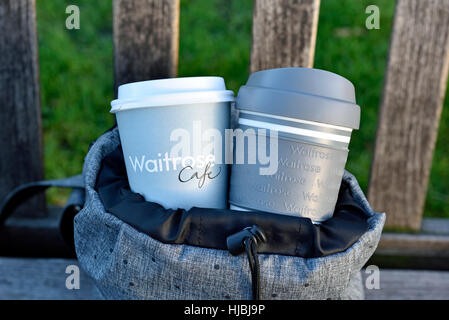 Waitrose emporter jetables et réutilisables tasse à café et tasse de voyage en sac à dos gris urbain intelligent sur banc de parc, le centre de Londres Banque D'Images