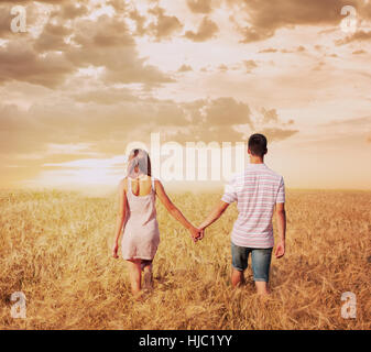 Jeune couple en train de marcher dans la zone pas au coucher du soleil holding hands Banque D'Images