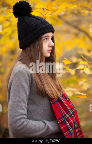 Profil d'une jolie adolescente portant bonnet de laine avec des couleurs automnales en arrière-plan Banque D'Images