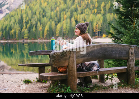 Woman relaxing on park bench, Lago di Braies, Cols Alpins, Val di Braies, Tyrol du Sud, Italie Banque D'Images