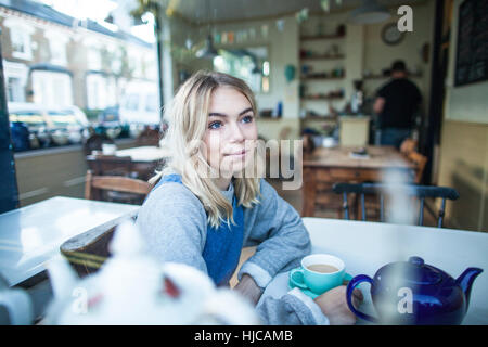 Jeune femme assise dans un café, à la fenêtre de Banque D'Images