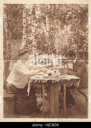 La photographie rétro. Famille à la table dans le jardin, vers 1905 Banque D'Images