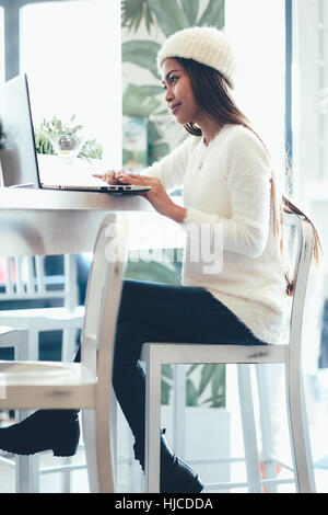 Belle fille en réseau dans un café avec un ordinateur portable Banque D'Images