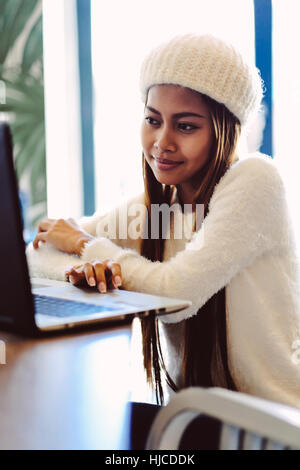 Belle fille en réseau dans un café avec un ordinateur portable Banque D'Images