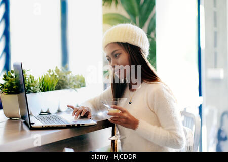 Belle fille en réseau dans un café avec un ordinateur portable Banque D'Images