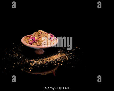 Ras el hanout, le mélange d'épices de luxe avec des pétales de rose. Typique de Maroc, l'Afrique du Nord. On reflective surface noire. Banque D'Images