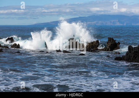 Vagues se brisant sur les rochers, sur la côte ouest de Tenerife avec l'île de La Gomera dans l'arrière-plan. Canaries, Espagne Banque D'Images