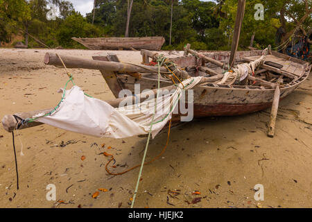 Grand bateau en bois pêcheur primitive sur plage avec des voiles blanches et fines mâts voile faites par les autochtones, Uzi Island, Zanzibar, Tanzania, Africa Banque D'Images