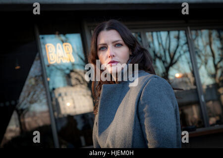 Dark haired woman attrayant à la caméra, à l'extérieur d'un bar Banque D'Images