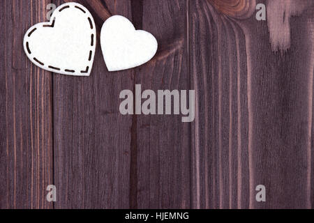 Deux coeurs de feutre blanc sur un fond de bois brun. Valentine Day. Carte de vœux. Wedding Banque D'Images