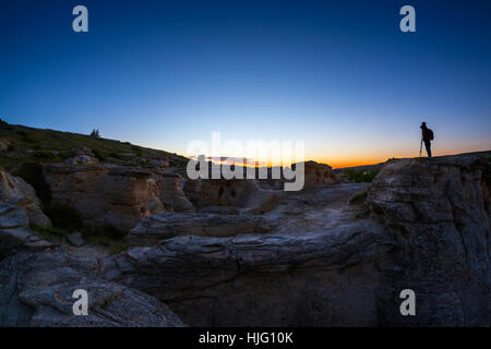 Silhouette de photographe sur haut de la cheminées à écrit sur la pierre d'attente du parc provincial de l'Alberta pour attraper le lever du soleil d'or à l'aube. Banque D'Images