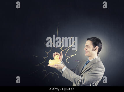 Funny businessman with yellow rubber duck toy Banque D'Images
