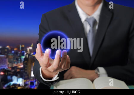 Tenir la main de l'homme d'affaires à billes bleu foncé sur fond de la ville de nuit résumé flou comme concept de l'innovation. Banque D'Images