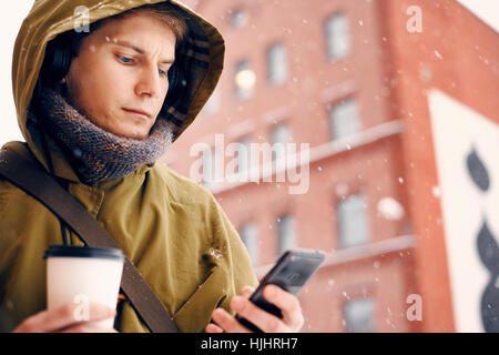 L'homme écoute de la musique sur le casque à l'hiver et boit du café Banque D'Images