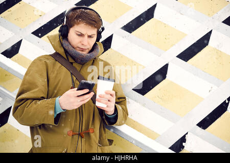 L'homme écoute de la musique sur le casque à l'hiver et boit du café Banque D'Images