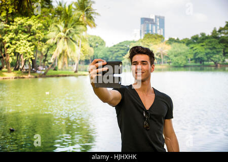 Beau jeune homme à l'extérieur dans le parc de la ville Banque D'Images