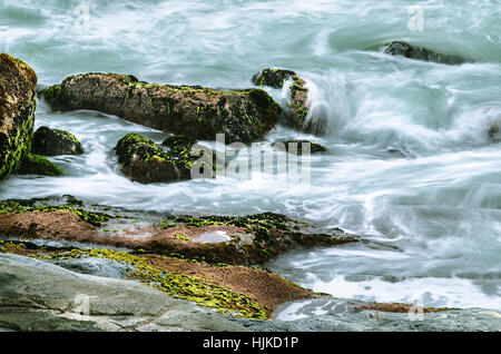 Une longue exposition photo de l'eau de mer fonctionnant sur les rochers. Banque D'Images